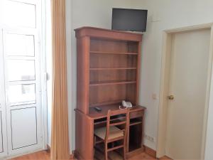 a wooden book shelf with a television on top of it at Hotel Alianca in Figueira da Foz