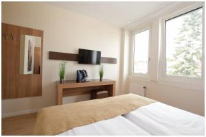 a bedroom with a bed and a desk and a television at Motel Plus Berlin in Berlin