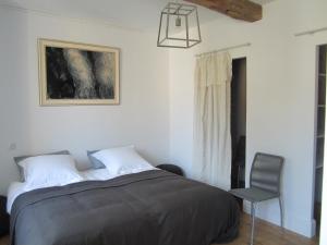 een slaapkamer met een bed en een stoel bij Maison Breton in Biran