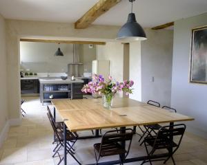een keuken met een houten tafel met bloemen in een vaas bij Maison Breton in Biran