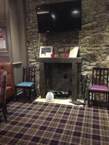 a living room with a fireplace with a tv on a stone wall at Burnett Arms in Inverurie