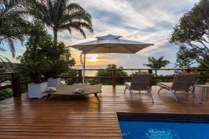a deck with an umbrella and chairs and a pool at Eco Vila Beija Flor in Búzios