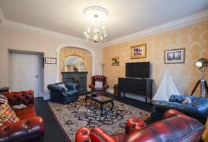 a living room with leather furniture and a chandelier at Reivers Apartment in Berwick-Upon-Tweed