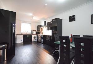 a kitchen with black cabinets and a table in it at Reivers Apartment in Berwick-Upon-Tweed +8 photos