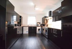 a large kitchen with black cabinets and white appliances at Reivers Apartment in Berwick-Upon-Tweed
