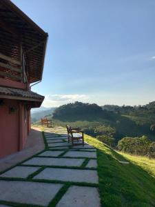 聖安東尼奧－杜皮尼亞爾的住宿－Repouso Mantiqueira，两座长椅坐在建筑物附近的小路上