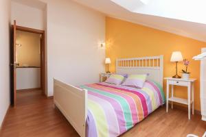 - une chambre avec un lit et une couverture rayée colorée dans l'établissement Relaxing Guesthouse - Sónias Houses, à Lisbonne