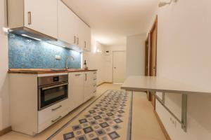 Relaxing Guesthouse - Sónias Houses في لشبونة: مطبخ بدولاب بيضاء وقمة كونتر