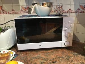 Un microondas sobre una encimera con un recipiente encima. en La Casetta di Andrea & Vale, en Termini Imerese