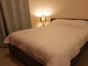 a bedroom with a white bed and a lamp at Haven Studio Apartments in Ras al Khaimah