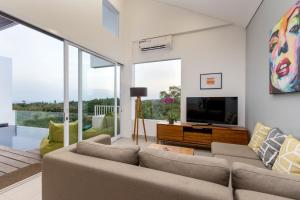 a living room with a couch and a tv at Villa Melati R3 Ungasan in Uluwatu