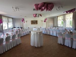 a room with rows of tables and chairs with pink flowers at Schollers Restaurant & Hotel in Rendsburg