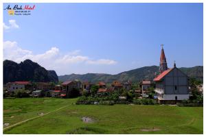 a small town with a church and a grass field at An Binh Homestay in Phong Nha +7 photos