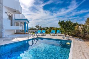 uma villa com uma piscina e cadeiras azuis em Aphrodite Luxury Villa Hersonissos em Hersonissos