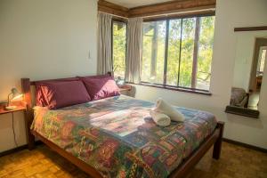 a bed in a room with a window and a bed with a comforter at Wyadup Brook Cottages in Yallingup