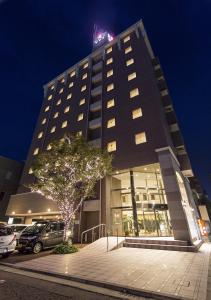 a tall building with cars parked in front of it at Imabari Urban Hotel (New Building) in Imabari