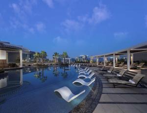 - une piscine avec des chaises longues dans un bâtiment dans l'établissement Hyatt Regency Dubai Creek Heights, à Dubaï