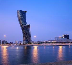 ein hohes Gebäude neben einem Wasserkörper in der Unterkunft Andaz Capital Gate Abu Dhabi - a concept by Hyatt in Abu Dhabi