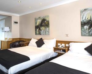 two beds in a hotel room with paintings on the wall at Blue Mountains Heritage Motel in Katoomba