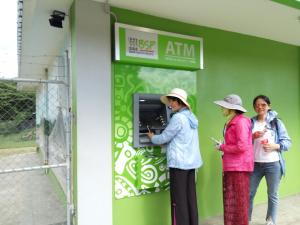 three women standing outside a green building with their cell phones at Castle Tree House And Bungalow in White Sands