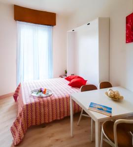 a bedroom with a bed with a table and a table at Laguna Grande monolocali in Bibione +16 photos