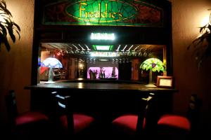 a bar in a bar with red chairs and a neon sign at Hotel Montetaxco in Taxco de Alarcón