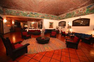 a living room with chairs and a table and a fireplace at Hotel Montetaxco in Taxco de Alarcón