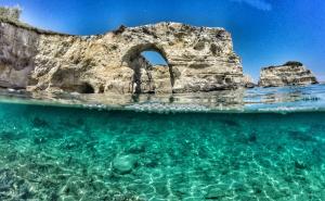 an arch in a rock formation in the water at Le Fiche d’India in Giuggianello