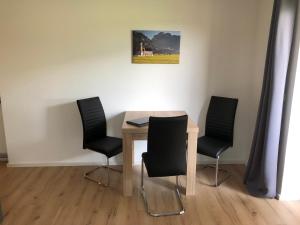 einen Tisch mit vier Stühlen und ein Gemälde an der Wand in der Unterkunft Ferienwohnung Hofer in Schwangau