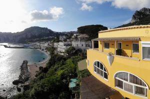 a yellow house with a view of a beach at B&B Punta Vivara in Capri
