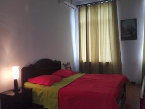 een slaapkamer met een bed met een rode en gele deken bij Hostel Mana Kutaisi in Koetaisi