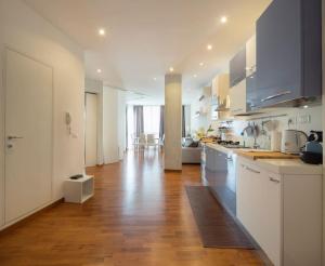 a kitchen with white cabinets and a wooden floor at Modern sunny apartment in residental area in Venice