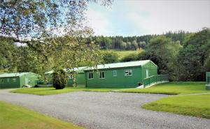 a green building with a gravel road in front of it at Glen Affric Holiday Park in Cannich