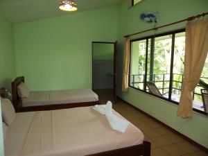 Habitación con 2 camas y ventana grande. en La Laguna del Lagarto Eco-Lodge, en Pital