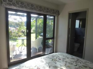 a bedroom with a bed and a large glass window at Idyllic Country Garden in Manakau