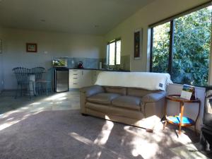 a living room with a couch and a kitchen at Idyllic Country Garden in Manakau