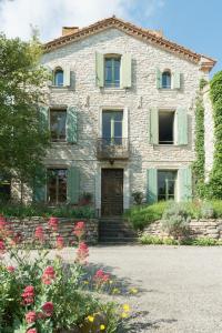 Cascastel-des-CorbièresにあるLa maison de maîtreの花の前の石造りの家