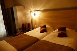 a hotel room with two beds and a chair at Logis Hôtel Le Lion d'Or in Chauvigny