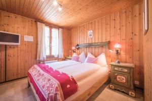 a bedroom with a large bed in a wooden room at Hotel Fassbind Beausite in Beatenberg