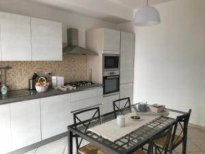 a kitchen with white cabinets and a table with chairs at La casa del Professore in Tortora
