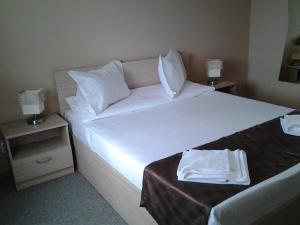 una camera da letto con un grande letto con lenzuola e cuscini bianchi di Hostel Nova Route a Mamaia Nord - Năvodari