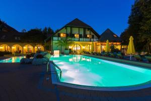 a swimming pool in front of a house at night at Hotel im Park in Bad Radkersburg