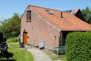 een klein bakstenen gebouw met een hond ervoor bij 't Huizeke in Asse