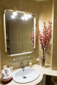 a bathroom sink with a mirror and a vase with flowers at Apartamento Garcilaso de la Vega in Cuenca