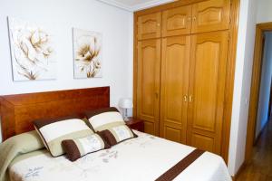 クエンカにあるApartamento Garcilaso de la Vegaのベッドルーム(ベッド1台、木製キャビネット付)