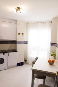 a white kitchen with a table and a sink at Apartamento Garcilaso de la Vega in Cuenca