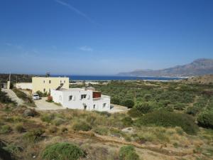 a white house on a hill with the ocean in the background at Beautiful spacious villa near Makry Gialos in Makry Gialos