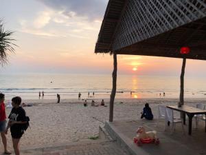 Lanta Seafront Resort في كو لانتا: مجموعة من الناس على الشاطئ عند غروب الشمس
