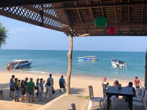 un groupe de personnes debout sur une plage avec des bateaux dans l'eau dans l'établissement Lanta Seafront Resort, à Ko Lanta