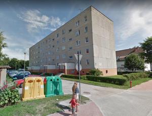 a young child is holding a street sign in front of a building at Apartament "KOMETA" Podczele in Kołobrzeg